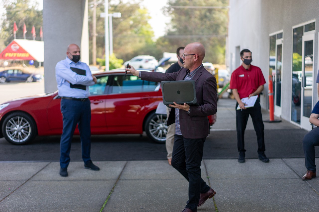 Auto dealer salesman on the floor talking to everyone