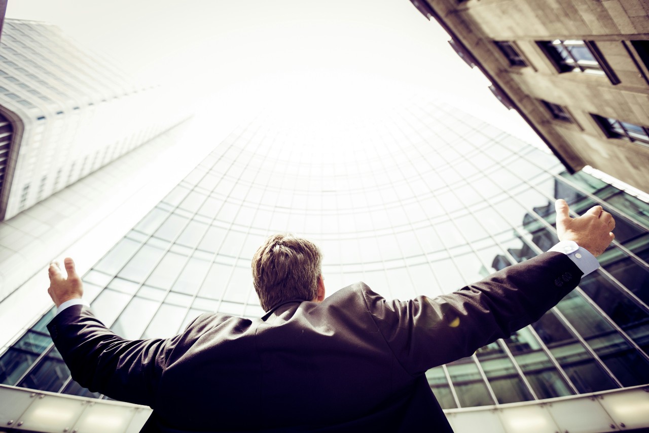 man looking up at business building feeling confident